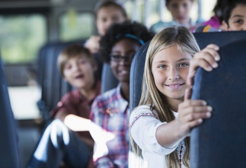 Children riding school bus Children (10-12 years) riding school bus. Focus on girl in foregound.